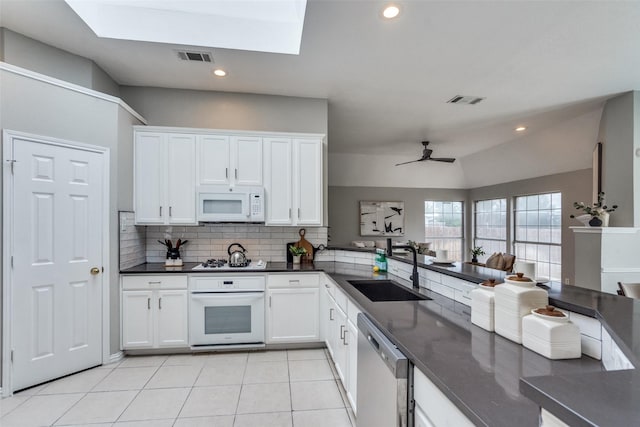 10715 Robincreek Ln, Frisco, TX 75035 - kitchen with white appliances, dark countertops, tasteful backsplash, white cabinetry, and light tile patterned flooring