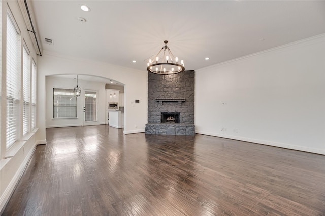 5513 Martel Ave, Dallas, TX 75206 - unfurnished living room featuring a chandelier, crown molding, a fireplace, arched walkways, and dark wood-style floors