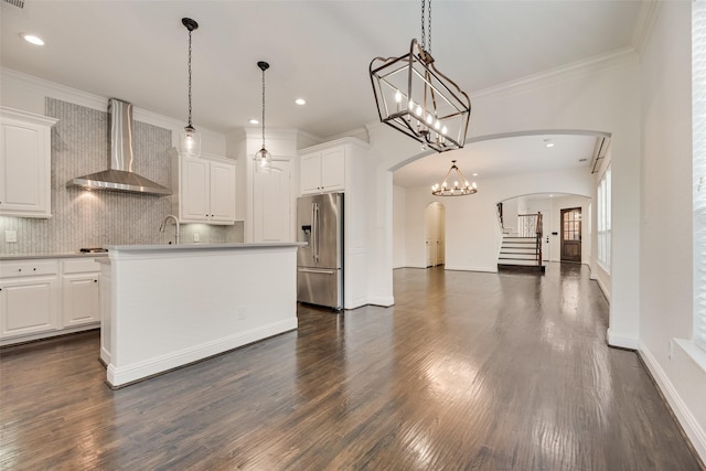 5513 Martel Ave, Dallas, TX 75206 - kitchen featuring stainless steel refrigerator with ice dispenser, wall chimney range hood, arched walkways, tasteful backsplash, and white cabinetry