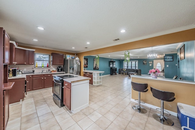 713 Keystone St, Mesquite, TX 75149 - kitchen featuring electric stove, stainless steel fridge, crown molding, light countertops, and a kitchen island with sink