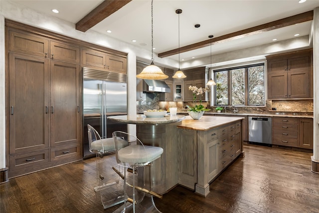 3619 Harvard Ave, Highland Park, TX 75205 - kitchen featuring appliances with stainless steel finishes, beam ceiling, tasteful backsplash, a kitchen bar, and dark wood-style floors