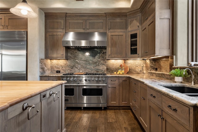 3619 Harvard Ave, Highland Park, TX 75205 - kitchen featuring high end appliances, wall chimney exhaust hood, dark wood finished floors, tasteful backsplash, and glass insert cabinets