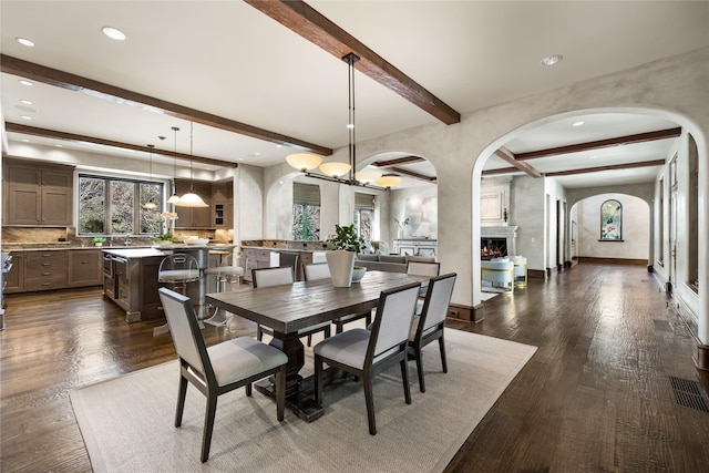 3619 Harvard Ave, Highland Park, TX 75205 - dining space featuring arched walkways, beamed ceiling, a large fireplace, a chandelier, and recessed lighting