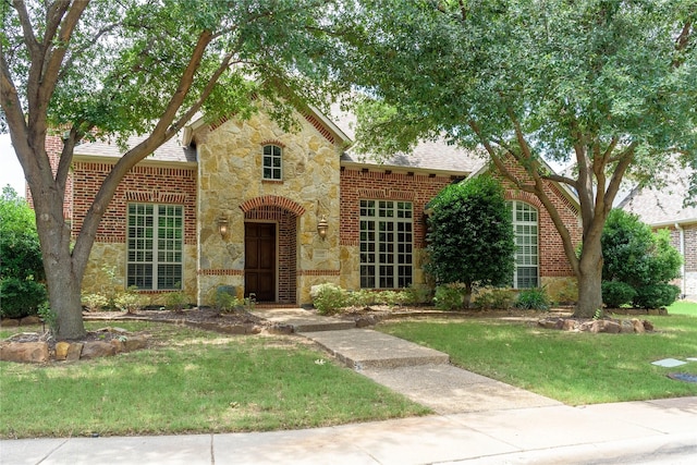 11819 Coronado Trl, Frisco, TX 75033 - view of front of house featuring stone siding, a front yard, brick siding, and a shingled roof