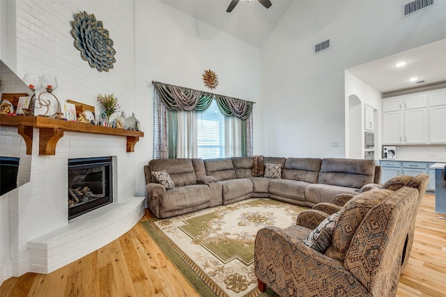 4017 Prickly Pear Ave, Aubrey, TX 76227 - living area featuring high vaulted ceiling, light wood-style floors, ceiling fan, a brick fireplace, and arched walkways