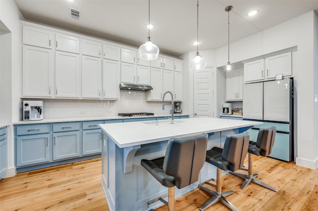 4017 Prickly Pear Ave, Aubrey, TX 76227 - kitchen with freestanding refrigerator, under cabinet range hood, backsplash, gas stovetop, and light wood-type flooring
