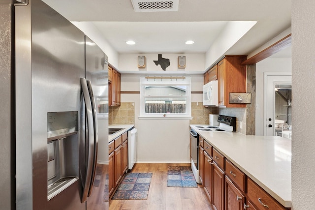 2318 Valleywood Dr, Carrollton, TX 75006 - kitchen featuring white appliances, light wood finished floors, decorative backsplash, brown cabinetry, and recessed lighting