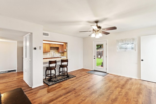 2318 Valleywood Dr, Carrollton, TX 75006 - kitchen featuring light countertops, ceiling fan, light wood finished floors, decorative backsplash, and a kitchen bar
