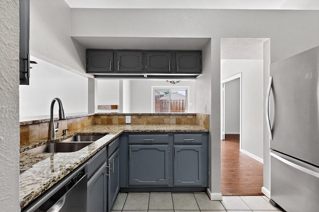 5644 Powers St, The Colony, TX 75056 - kitchen featuring appliances with stainless steel finishes, light tile patterned flooring, light stone countertops, and gray cabinets