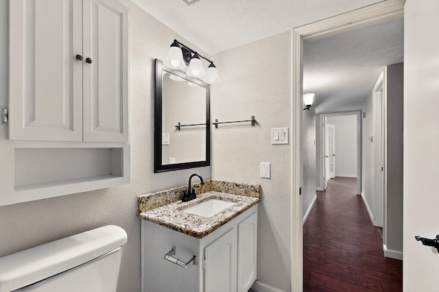 5644 Powers St, The Colony, TX 75056 - half bath with a textured wall, wood finished floors, vanity, and a textured ceiling