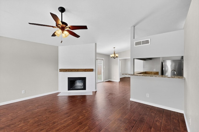 5644 Powers St, The Colony, TX 75056 - unfurnished living room featuring dark wood-style flooring, a large fireplace, ceiling fan, a chandelier, and vaulted ceiling