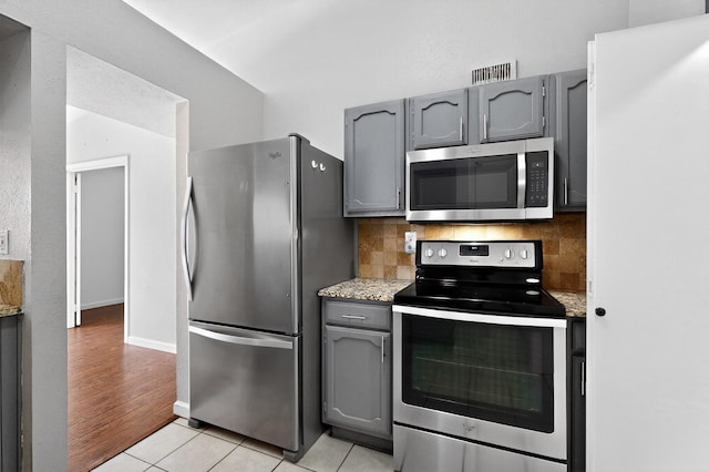 5644 Powers St, The Colony, TX 75056 - kitchen with appliances with stainless steel finishes, gray cabinets, backsplash, and light tile patterned floors