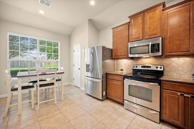 1224 Shelley Dr, Burleson, TX 76028 - kitchen featuring stainless steel appliances, tasteful backsplash, dark stone countertops, brown cabinetry, and recessed lighting