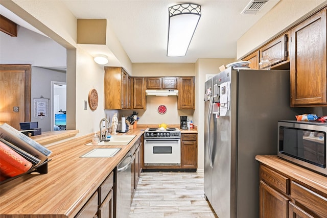 406 Anice Ln, Euless, TX 76039 - kitchen featuring appliances with stainless steel finishes, light wood finished floors, under cabinet range hood, and wood counters