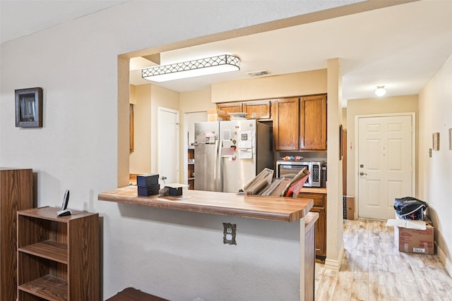 406 Anice Ln, Euless, TX 76039 - kitchen with refrigerator with ice dispenser, stainless steel microwave, brown cabinetry, and light wood-type flooring