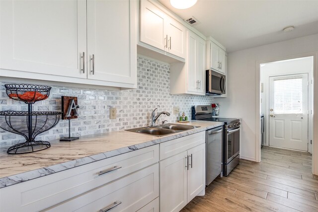 162 Aztec Dr, Mabank, TX 75156 - kitchen featuring appliances with stainless steel finishes, white cabinetry, tasteful backsplash, light countertops, and light wood finished floors