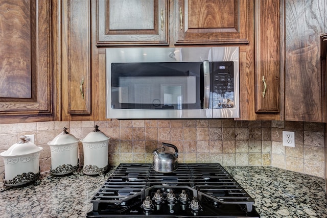 128 Country Club Dr, Heath, TX 75032 - detailed view of stainless steel microwave, stovetop, tasteful backsplash, and stone countertops
