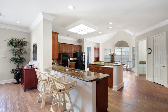 128 Country Club Dr, Heath, TX 75032 - kitchen with black appliances, a breakfast bar area, a chandelier, light wood finished floors, and ornamental molding