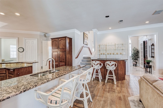 128 Country Club Dr, Heath, TX 75032 - kitchen featuring a breakfast bar area, light stone counters, ornamental molding, light wood-type flooring, and recessed lighting