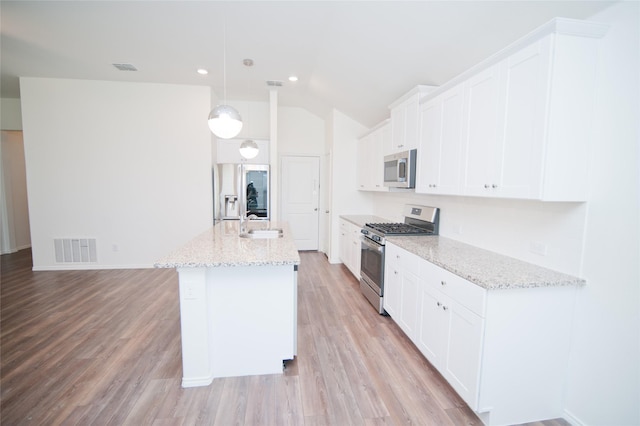 3913 Great Plains Way, Forney, TX 75126 - kitchen with stainless steel appliances, lofted ceiling, light wood-type flooring, an island with sink, and white cabinetry