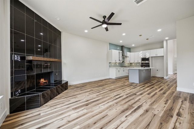 15578 Wrangler Dr, Frisco, TX 75035 - unfurnished living room with light wood-type flooring, a tile fireplace, ceiling fan, and recessed lighting