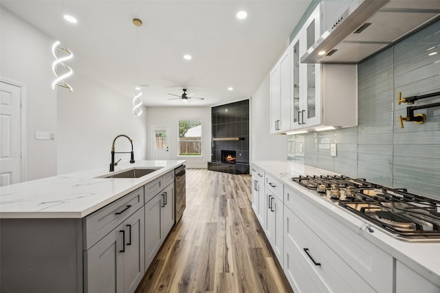15578 Wrangler Dr, Frisco, TX 75035 - kitchen featuring appliances with stainless steel finishes, exhaust hood, a ceiling fan, a fireplace, and gray cabinets