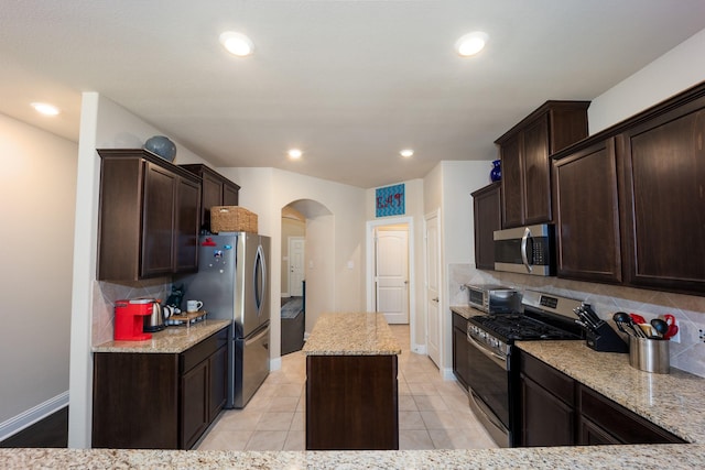 3508 Cooke Ln, Melissa, TX 75454 - kitchen featuring appliances with stainless steel finishes, arched walkways, tasteful backsplash, dark brown cabinets, and recessed lighting