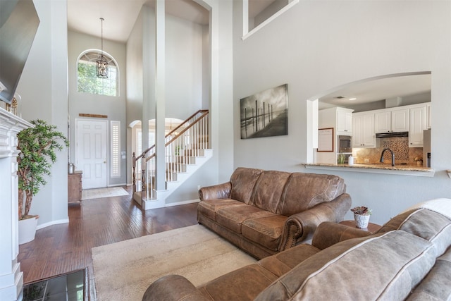 8508 Forsythia Dr, Mckinney, TX 75072 - living room featuring a towering ceiling, arched walkways, stairway, a chandelier, and wood finished floors