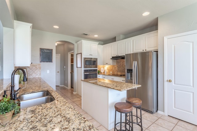 8508 Forsythia Dr, Mckinney, TX 75072 - kitchen featuring appliances with stainless steel finishes, arched walkways, under cabinet range hood, backsplash, and recessed lighting