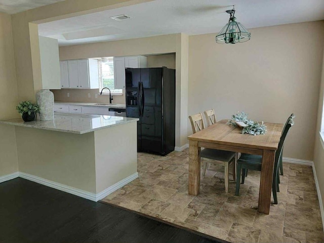 4737 Lawler Rd, Garland, TX 75042 - kitchen with black fridge, white cabinetry, a peninsula, light stone counters, and hanging light fixtures