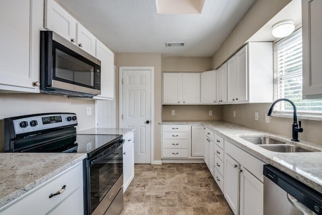 4737 Lawler Rd, Garland, TX 75042 - kitchen with stainless steel appliances, white cabinetry, and stone finish flooring