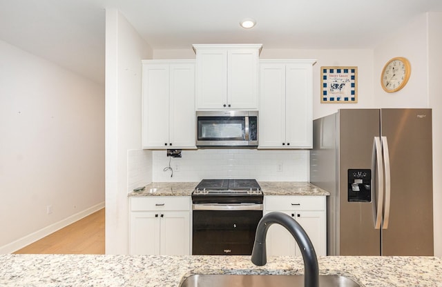1103 Witherspoon Ln, Princeton, TX 75407 - kitchen featuring appliances with stainless steel finishes, light wood finished floors, white cabinets, and backsplash