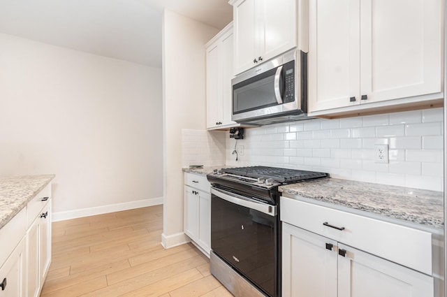 1103 Witherspoon Ln, Princeton, TX 75407 - kitchen featuring appliances with stainless steel finishes, light wood-style flooring, tasteful backsplash, white cabinets, and light stone counters