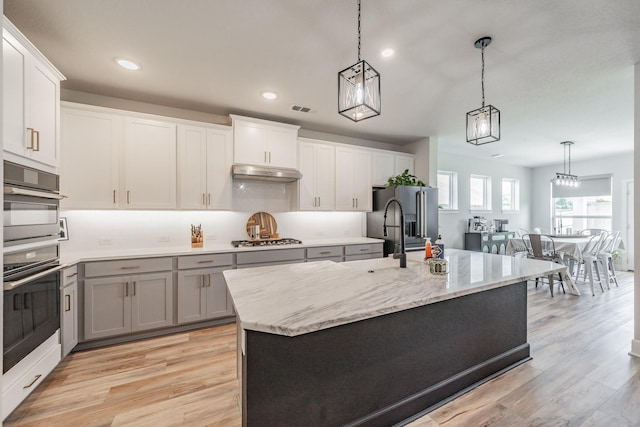 2420 Stella Ln, Northlake, TX 76247 - kitchen with stainless steel appliances, light wood-style flooring, hanging light fixtures, under cabinet range hood, and light stone countertops