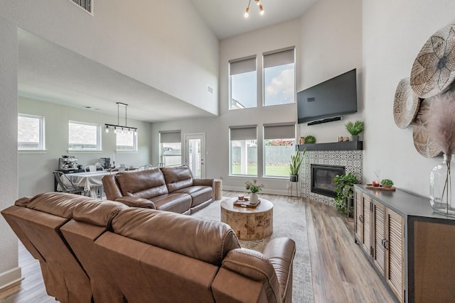 2420 Stella Ln, Northlake, TX 76247 - living room with light wood-style flooring, a fireplace, a chandelier, and a towering ceiling