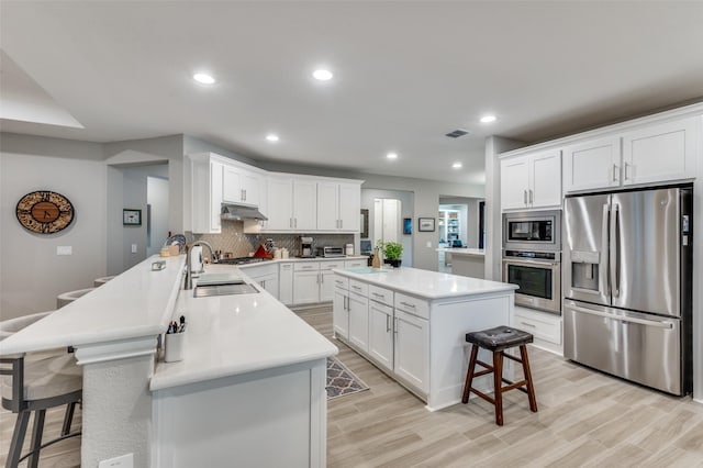 1116 Cornerstone Dr, Little Elm, TX 76227 - kitchen with appliances with stainless steel finishes, a kitchen breakfast bar, under cabinet range hood, backsplash, and a peninsula