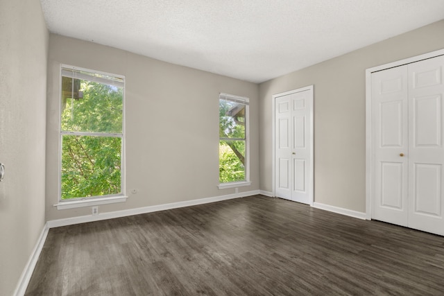 6050 Melody Ln Unit 341, Dallas, TX 75231 - unfurnished bedroom featuring dark wood-type flooring and two closets