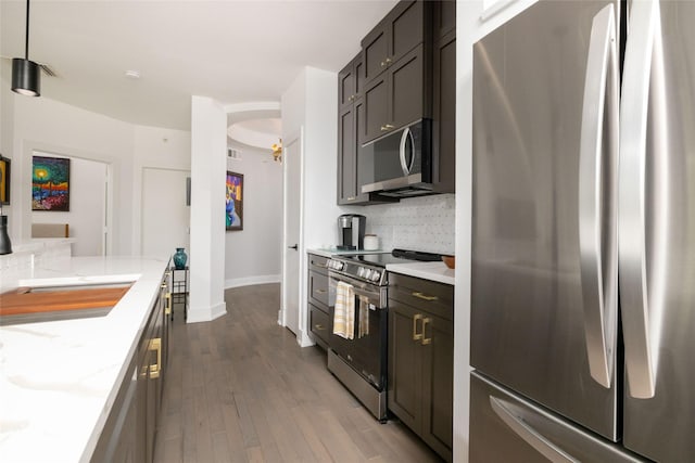 4333 Gilbert Ave Unit 330, Dallas, TX 75219 - kitchen featuring appliances with stainless steel finishes, decorative backsplash, dark wood finished floors, and light stone counters