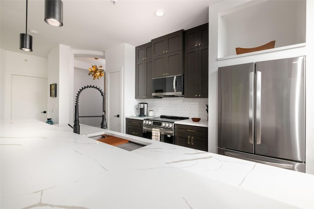4333 Gilbert Ave Unit 330, Dallas, TX 75219 - kitchen featuring appliances with stainless steel finishes, hanging light fixtures, backsplash, light stone counters, and arched walkways