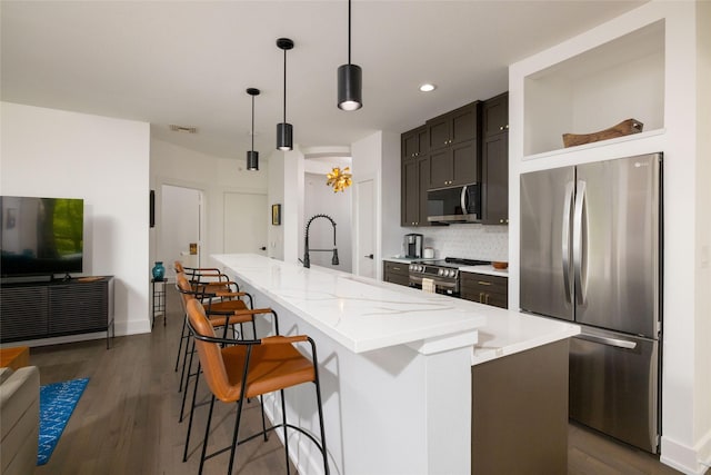 4333 Gilbert Ave Unit 330, Dallas, TX 75219 - kitchen with appliances with stainless steel finishes, dark wood finished floors, decorative backsplash, a center island with sink, and a kitchen bar