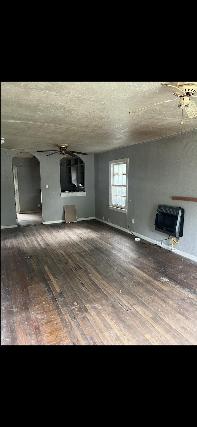 1026 Peak St, Denton, TX 76201 - unfurnished living room with ceiling fan, heating unit, hardwood / wood-style floors, arched walkways, and a textured ceiling