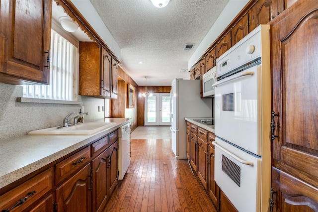 328 Bennett Cir, Desoto, TX 75115 - kitchen featuring french doors, a textured ceiling, white appliances, light countertops, and hardwood / wood-style flooring