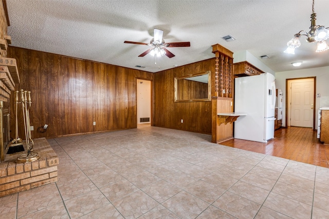 328 Bennett Cir, Desoto, TX 75115 - unfurnished living room with wooden walls, a chandelier, a ceiling fan, and a textured ceiling