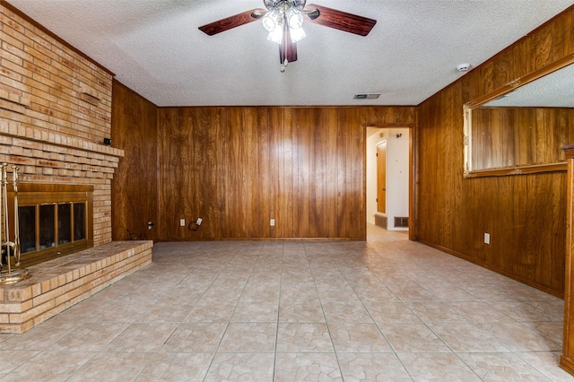 328 Bennett Cir, Desoto, TX 75115 - unfurnished living room featuring a textured ceiling, a ceiling fan, wood walls, and a fireplace