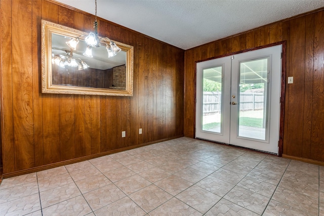 328 Bennett Cir, Desoto, TX 75115 - unfurnished dining area featuring wooden walls, french doors, and a textured ceiling