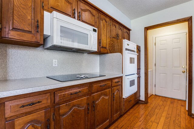 328 Bennett Cir, Desoto, TX 75115 - kitchen featuring white appliances, light countertops, decorative backsplash, light wood-style floors, and a textured ceiling