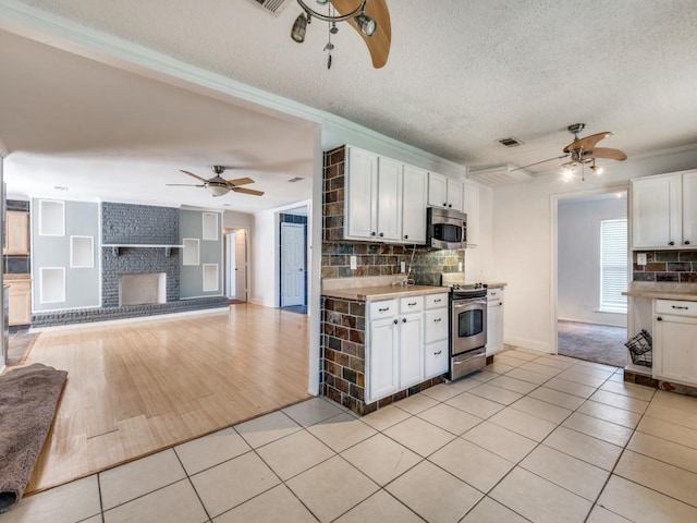 3836 Diamond Loch E, North Richland Hills, TX 76180 - kitchen featuring stainless steel appliances, a ceiling fan, white cabinetry, light tile patterned floors, and a textured ceiling