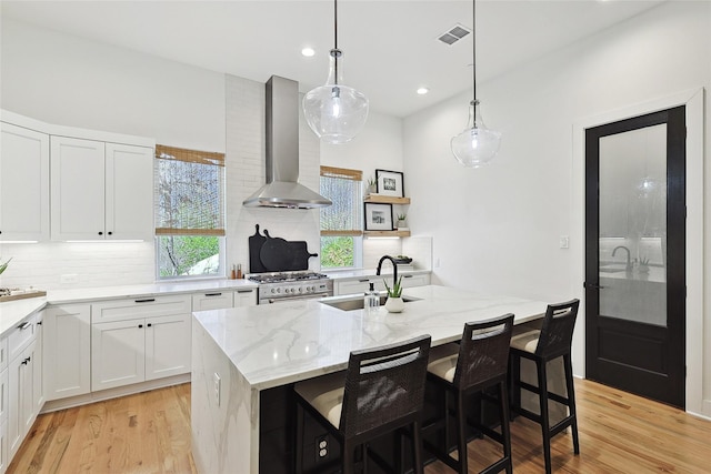 354 Foch St, Fort Worth, TX 76107 - kitchen with wall chimney exhaust hood, stainless steel range, backsplash, light stone counters, and white cabinets