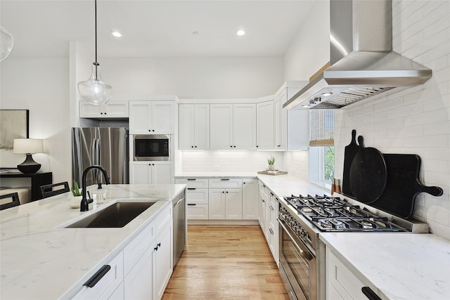 354 Foch St, Fort Worth, TX 76107 - kitchen with wall chimney range hood, appliances with stainless steel finishes, white cabinets, light wood-style floors, and hanging light fixtures