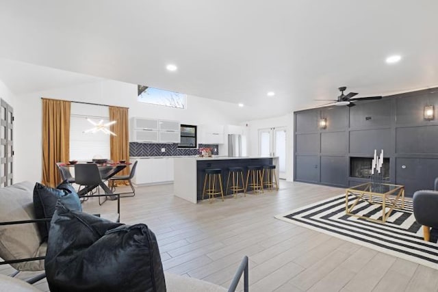 10669 Larchfield Ln, Dallas, TX 75238 - living room with lofted ceiling, light wood-style flooring, a fireplace, ceiling fan, and recessed lighting